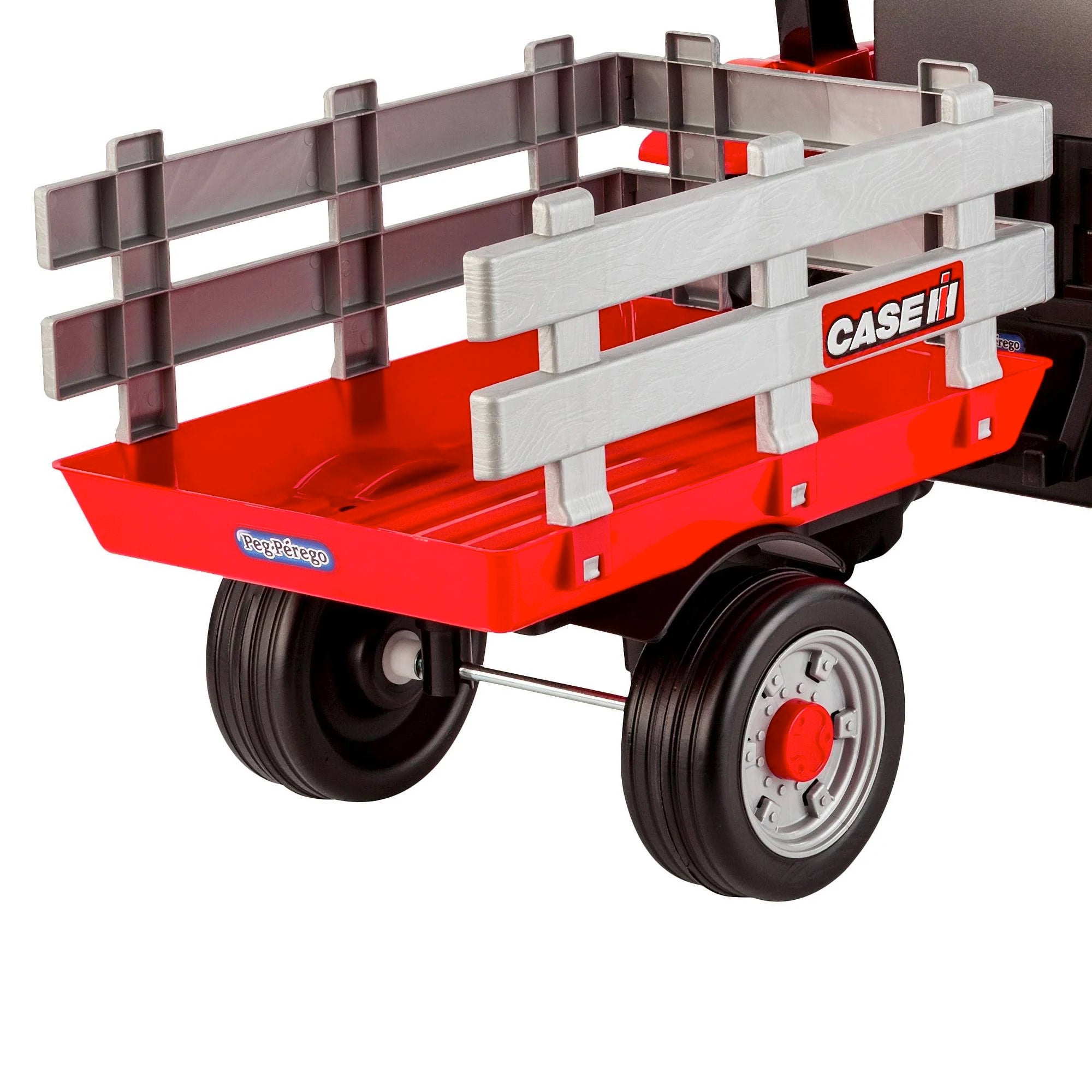 Red children's pedal tractor with large black wheels and detachable gray stake-side trailer for outdoor play