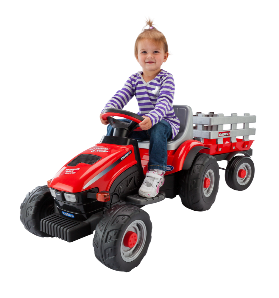 Toddler smiling on red ride-on tractor with detachable trailer, black wheels, and gray seat