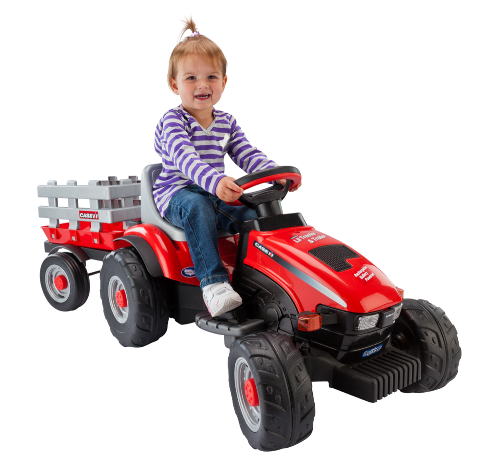 Toddler smiling on bright red ride-on tractor with detachable gray trailer, holding steering wheel, facing right