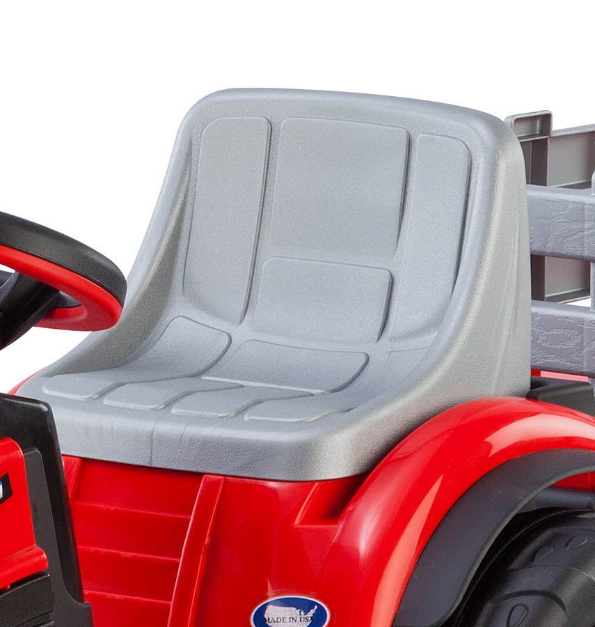 Red children's ride-on tractor with gray molded seat, black steering wheel with red accent, and detachable trailer.