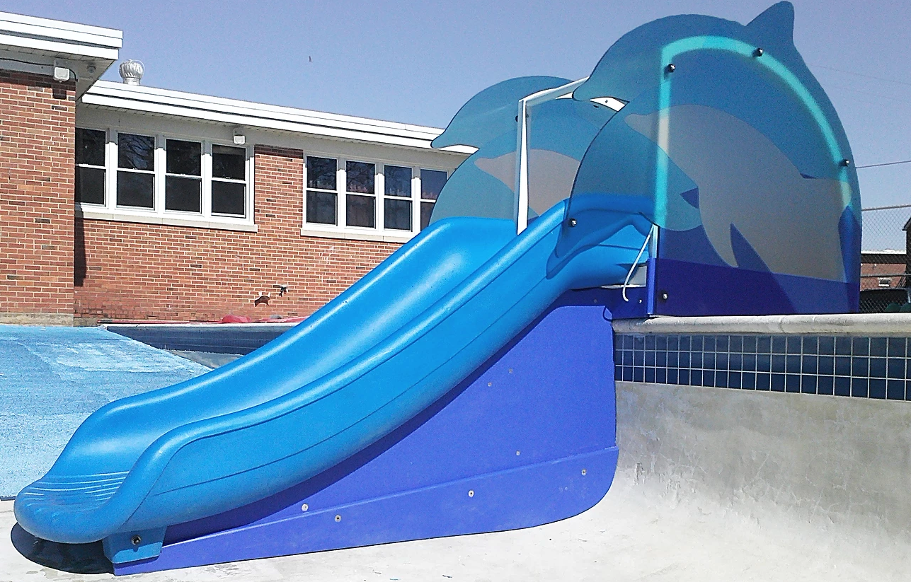 Blue commercial water slide with dolphin-themed side panels installed at an empty pool deck