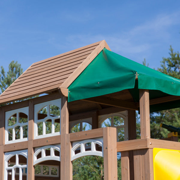 Two-level wooden playset clubhouse with white-framed windows, green canopy roof, outdoor telescope, and decorative details