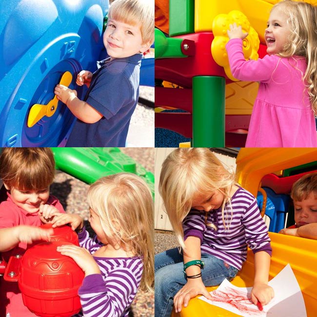 Toddlers playing on a colorful multi-activity playground with a clock panel, flower wheel, drum, and playhouse window.
