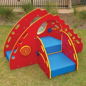 Colorful toddler playground climber with red panels, blue soft deck, handholds, and climbing features on grass