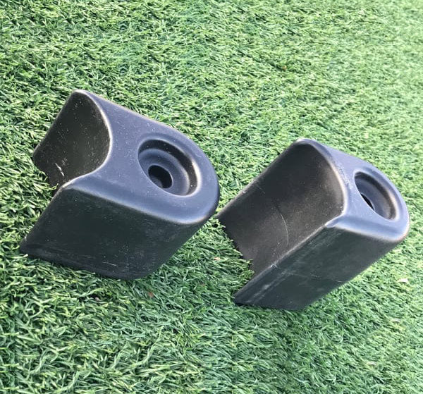 Two black plastic playground border filler ends with circular holes on artificial green turf