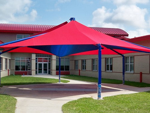 Mariner Hexagon Shade Structure with 6 posts, red and blue layered fabric canopy shading paved area near school building