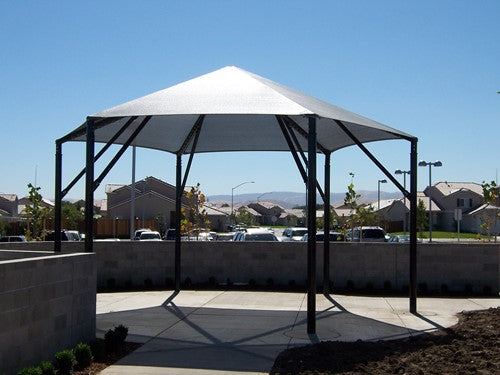 Hexagonal outdoor shade canopy with six black posts over paved area providing sun protection
