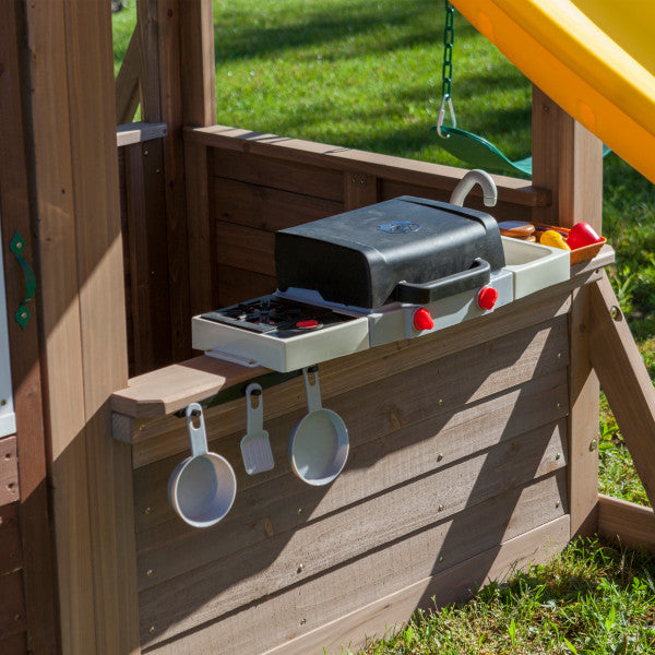 Lower clubhouse of wooden playset with attached play BBQ grill, sink, utensils, and toy food accessories