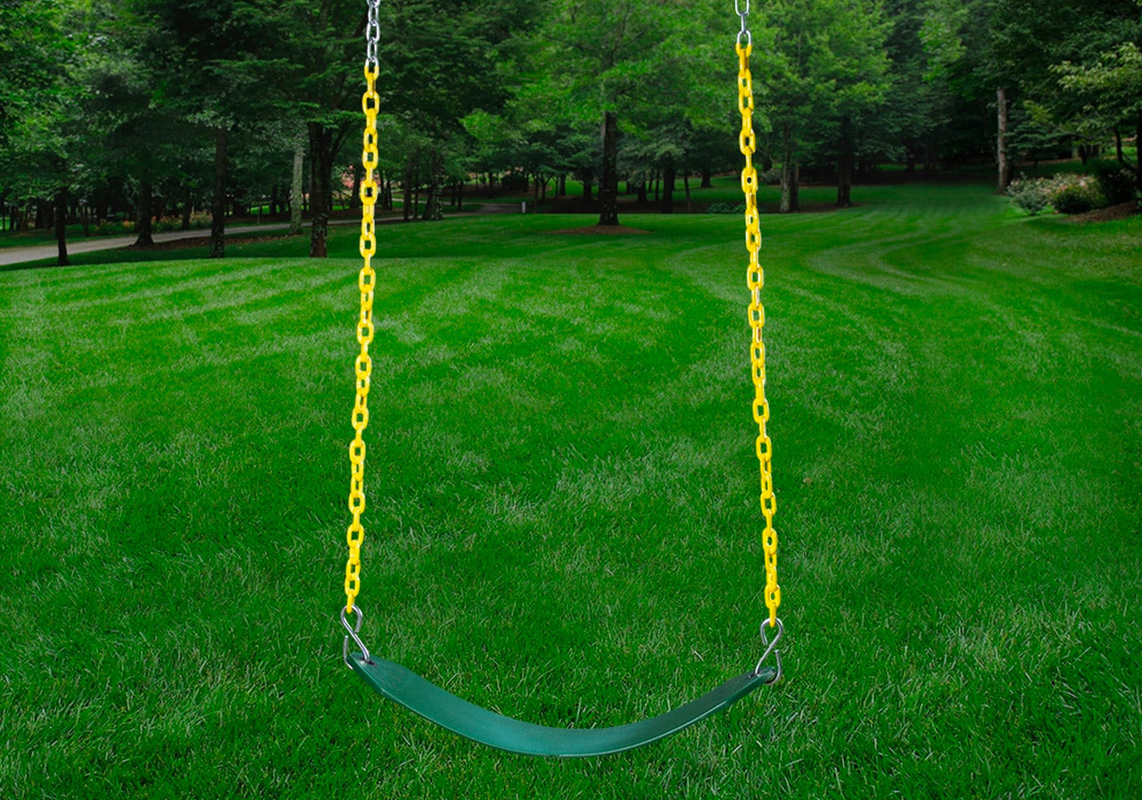 Green belt swing with yellow plastic chains hanging in a grassy backyard surrounded by trees