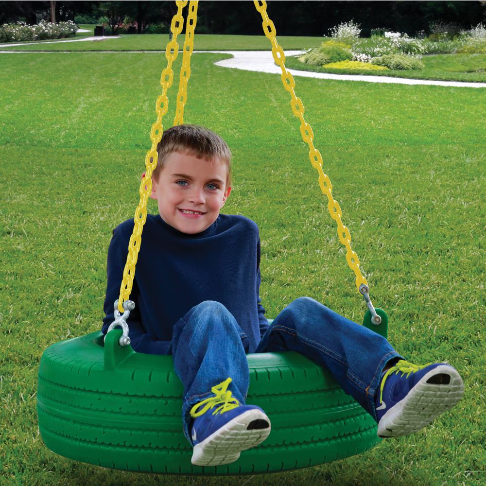 Child sitting on green 360° turbo tire swing with yellow chains on grassy lawn