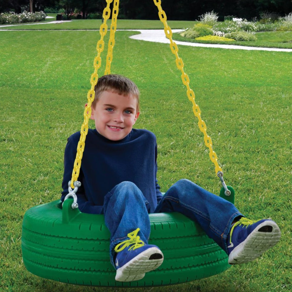 Child sitting on green tire swing with yellow chains in grassy park setting