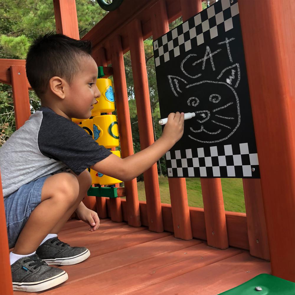 Child drawing a cat face with chalk on a tic-tac-toe panel attached to a cedar wooden playset deck