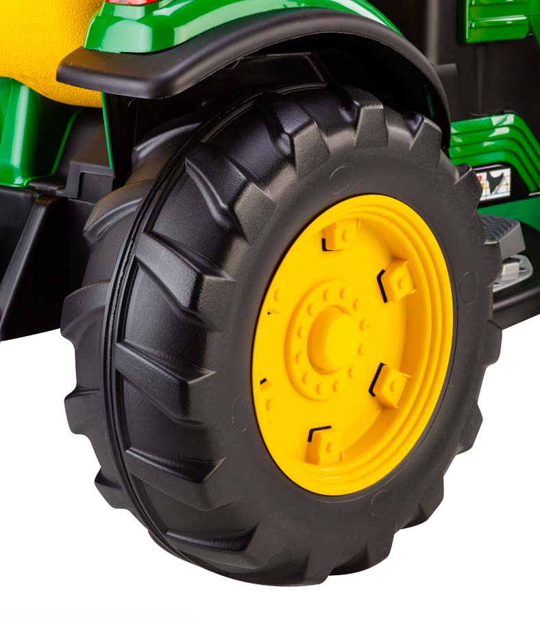 Close-up of a large black tire with deep treads and bright yellow rim on a green and yellow ride-on tractor toy
