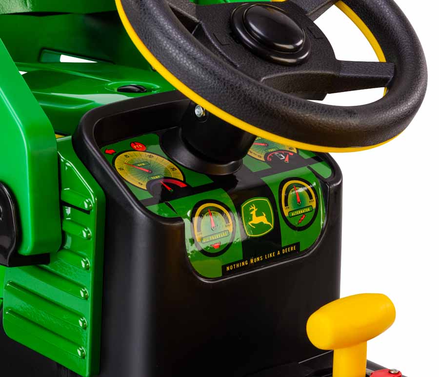 Green and black ride-on tractor dashboard with steering wheel, yellow gear shift, and gauge-style decals on a John Deere loader vehicle