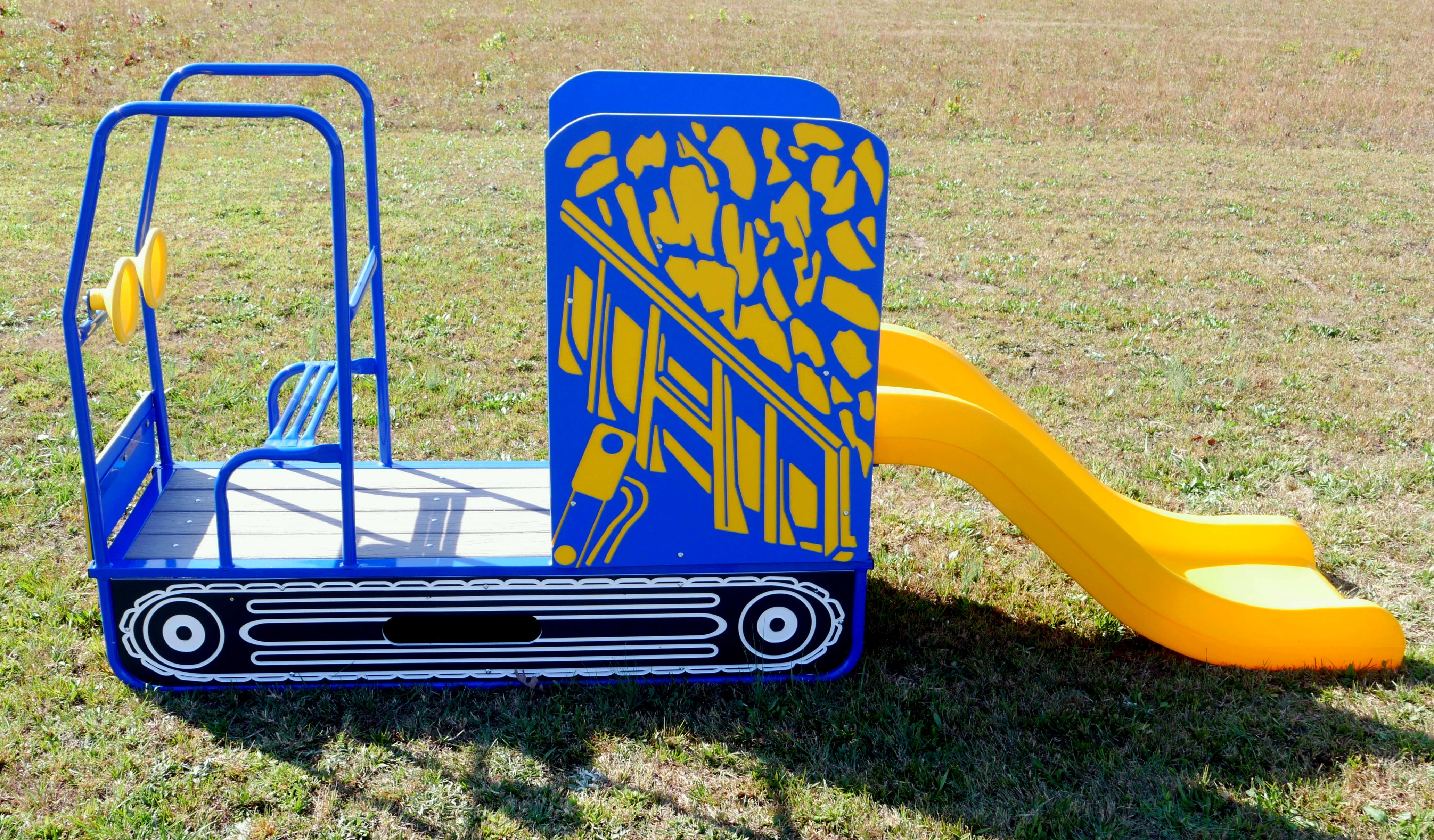 Bright blue and yellow dump-truck themed playground slide with twin steering wheels, climbing steps, and front bench on grass