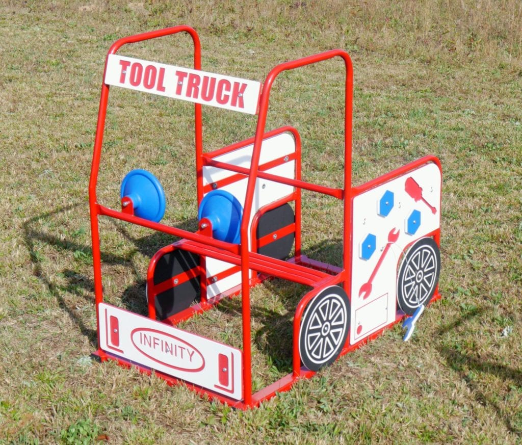 Red metal outdoor play structure shaped like a truck with interactive tool-themed panels and blue steering wheels