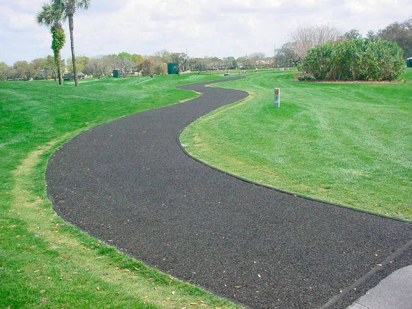 Curved black recycled rubber playground border edging containing loose fill surfacing along green grassy park area