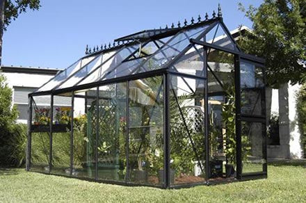 Junior Victorian Greenhouse with black aluminum frame, tempered glass panels, automatic roof windows, and lush plants inside