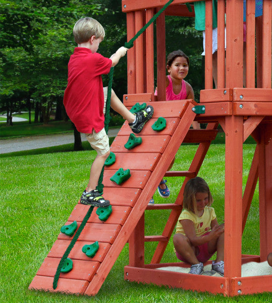 Cedar wooden playset with climbing wall, rope, sandbox, swings, and children playing on grass outdoors