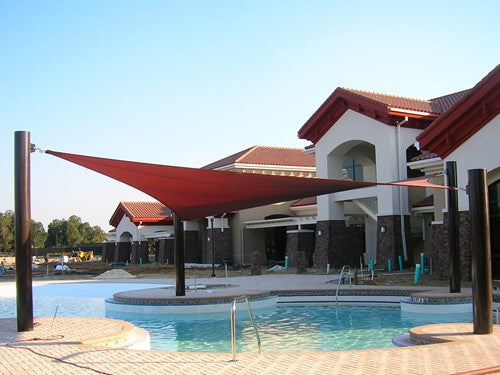 4 Point Hypar Sail Shade Structure with red hyperbolic fabric stretched over four black columns by a poolside at a residential complex