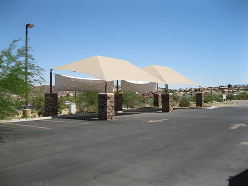 Slanted Hip Shade Structure with 4 Posts featuring beige sloped canopy supported by stone pillars in outdoor parking area under clear sky