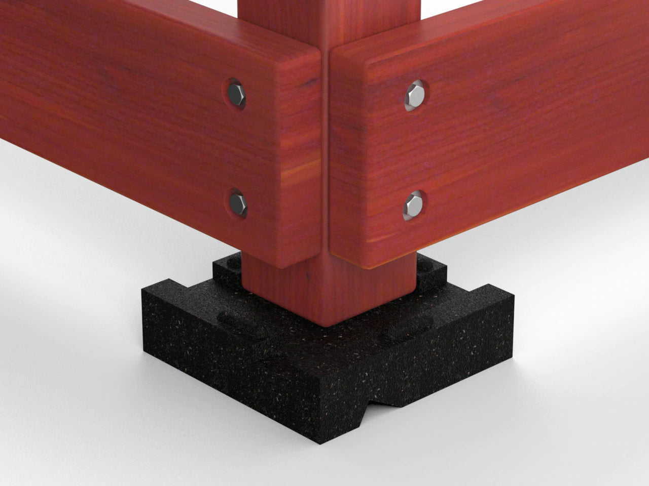 Close-up of wooden playset corner post resting on a black textured leveling block for moisture protection and stability