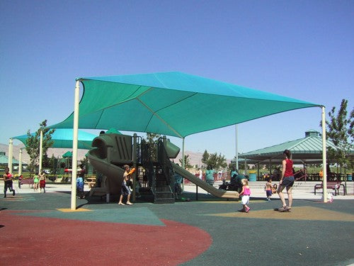 Teal rectangular hip roof shade structure with four posts covering playground equipment and children playing underneath