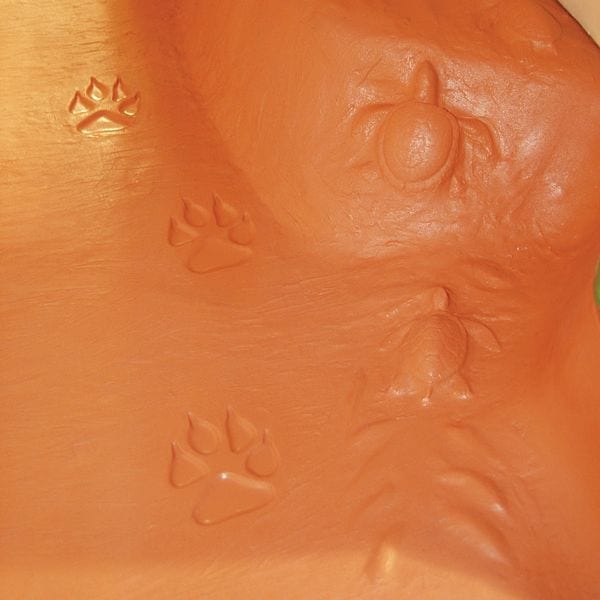 Textured orange playhouse surface with raised animal paw prints and insect shapes for tactile sensory play.