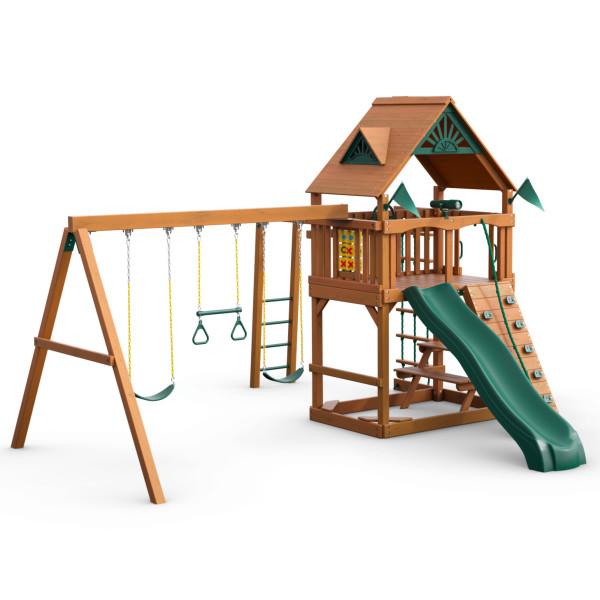 Cedar wooden swing set with green slide, two belt swings, trapeze bar, rock climbing wall, and tic-tac-toe panel
