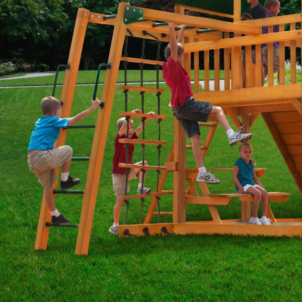 Cedar wooden swing set with monkey bars, rope ladder, climbing wall, picnic table, and children playing on grass
