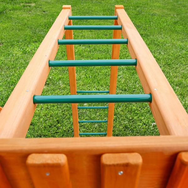 Overhead view of wooden monkey bars with green metal rungs on amber-stained cedar frame over grass