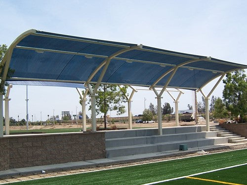 Curved blue canopy arch shade structure over outdoor concrete seating near sports field