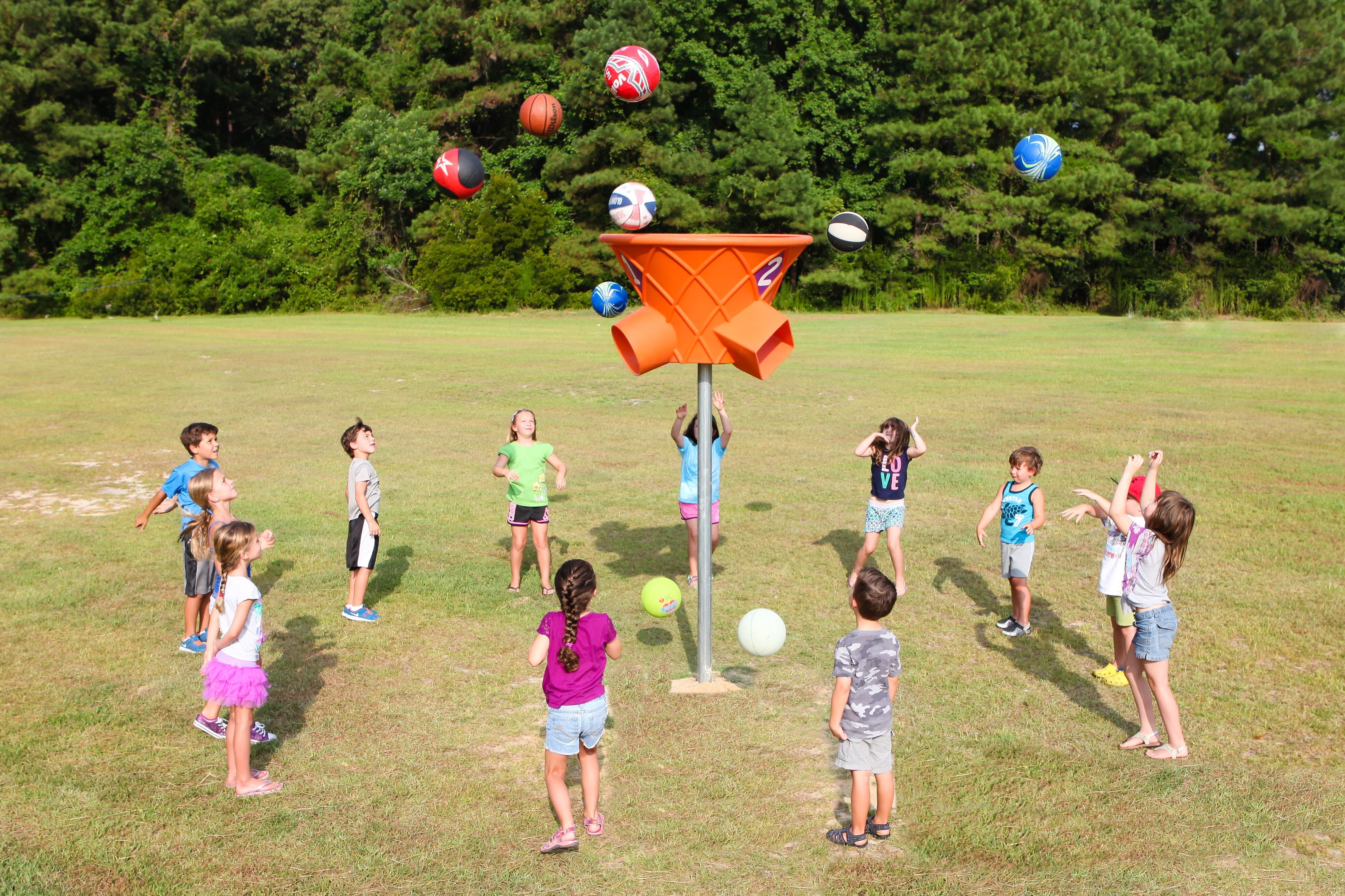 Three-sided orange ball game structure outdoors with colorful balls in midair and children playing around it