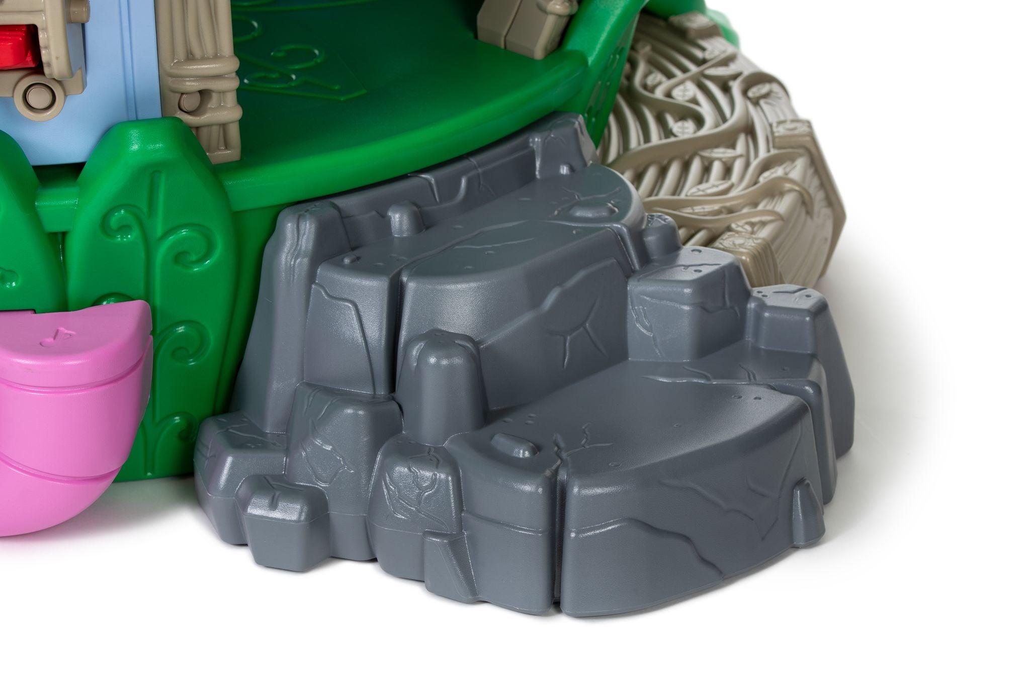 Nature-themed toddler playground rock climber with gray boulder steps, green platform edge, tree-root texture, pink accent