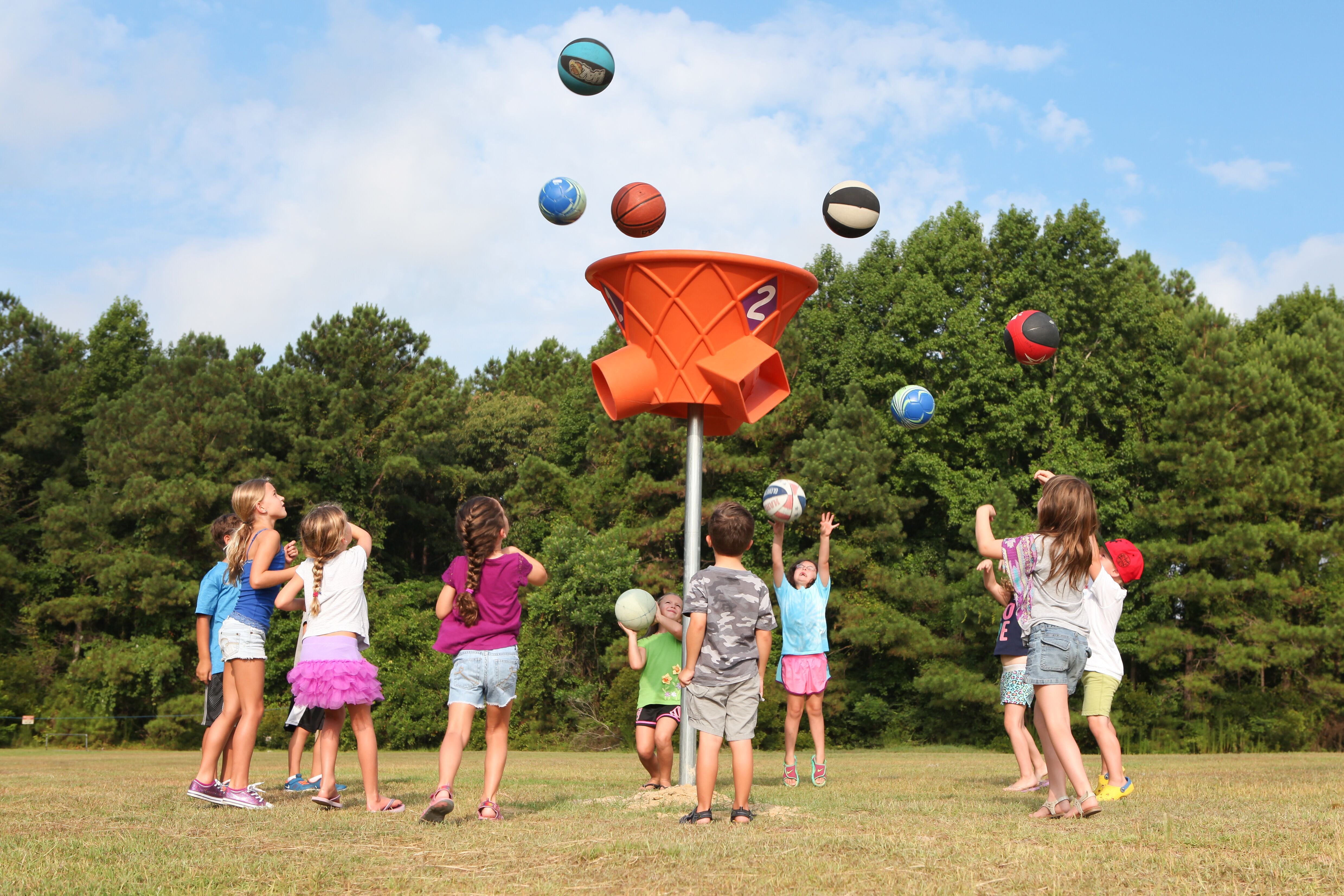 Three-sided orange playground ball game hoop outdoors with colorful balls in midair during active play