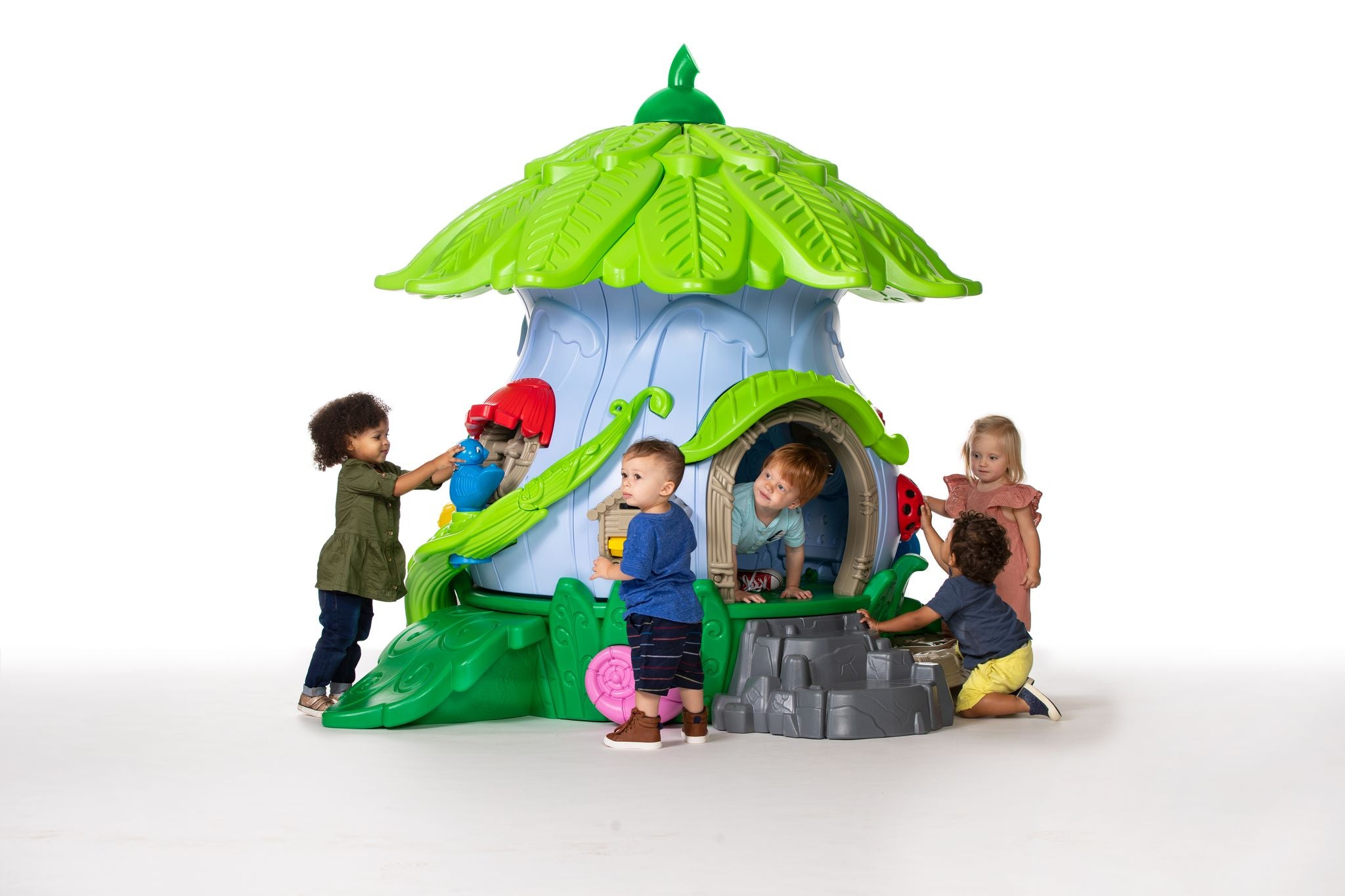Nature-themed toddler playground playhouse with leaf roof, sensory panels and crawl door; kids explore mushrooms, ladybug