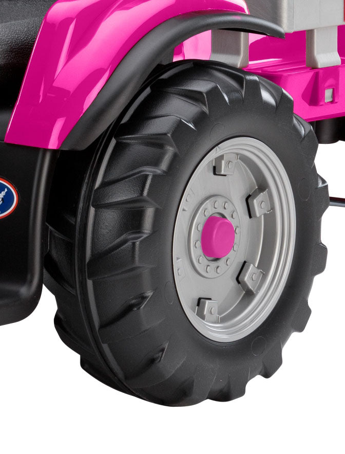 Large black tractor wheel with deep treads and pink hub on a pink ride-on tractor with detachable stake-side trailer