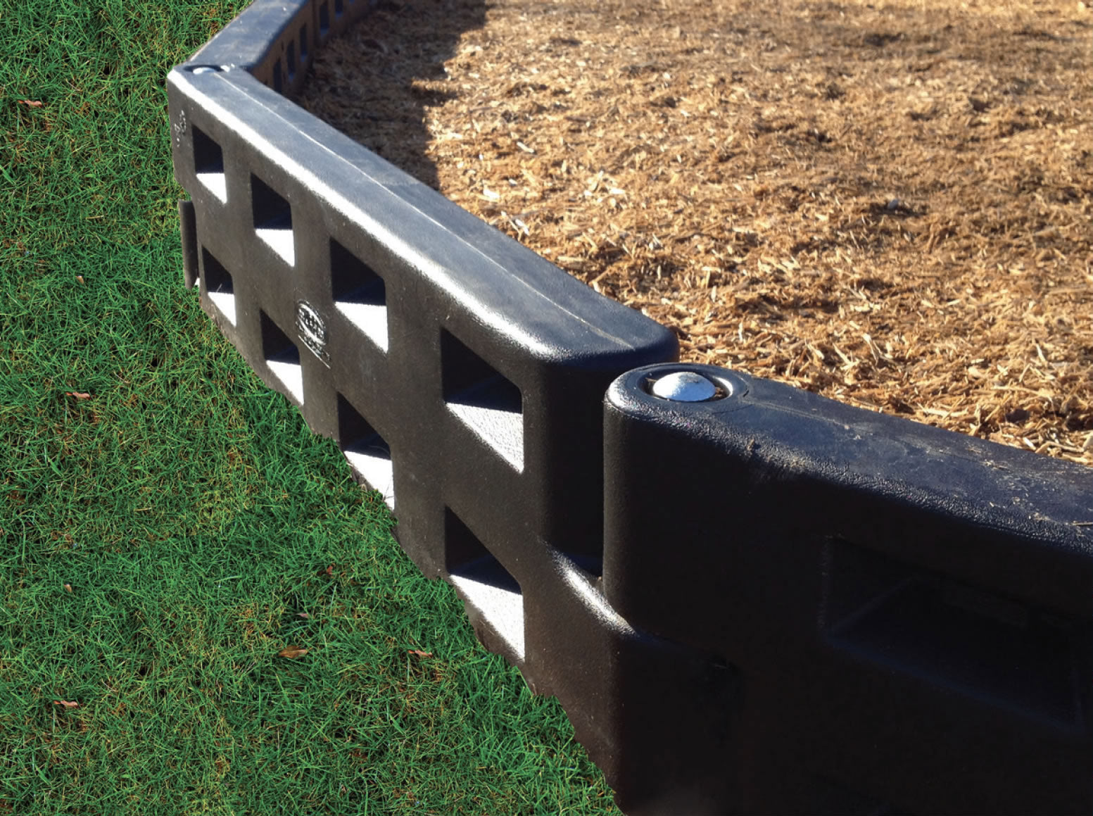 Black Plastic Playground Border with Spike edging wood chip surface and grass, durable lightweight retaining system