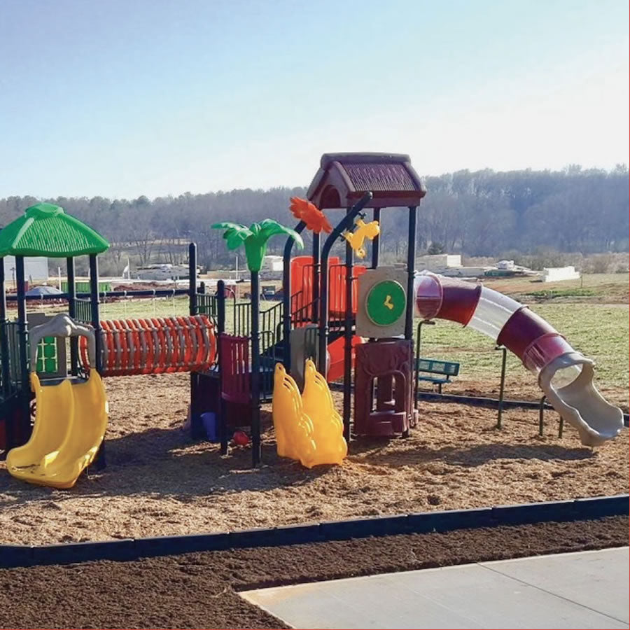 Durable black plastic playground border with spike enclosing colorful children's play structure with slides and climbing features