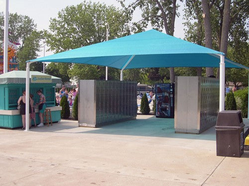 Blue hip roof shade structure with four white posts covering two rows of outdoor metal lockers in a park setting