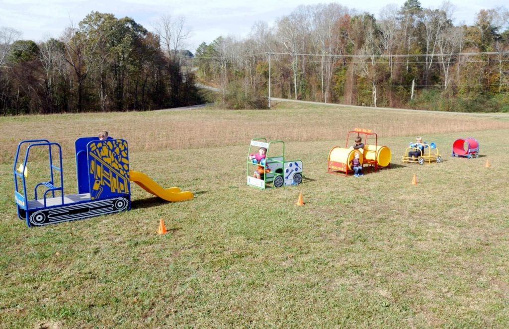 Colorful outdoor construction-themed play set with small children engaging in imaginative teamwork and creative play.