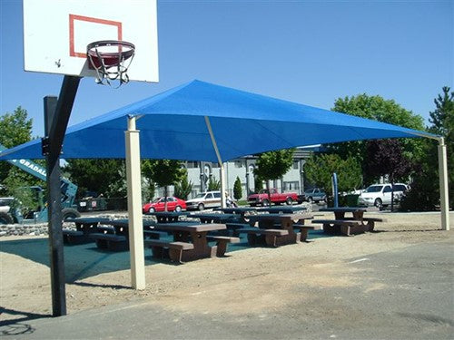Blue pyramid roof shade structure with four posts covering picnic tables near a basketball hoop in a park setting