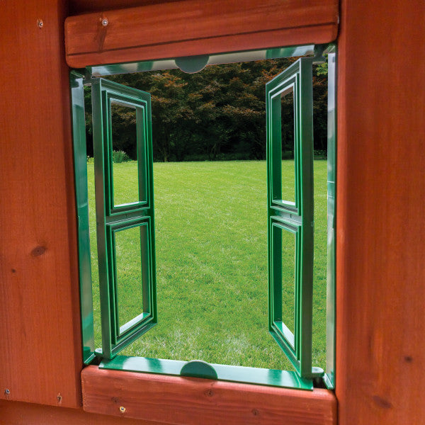 Redwood-stained wooden playset with green double-panel window and working shutters overlooking grassy yard