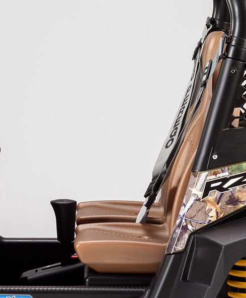Tan bucket seats and camo-patterned side panel with seatbelt on a Polaris RZR 900 ride-on vehicle interior detail