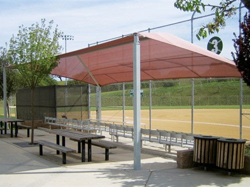 Slanted hip shade structure with four posts over bleachers at a baseball field providing sun protection and foul ball safety