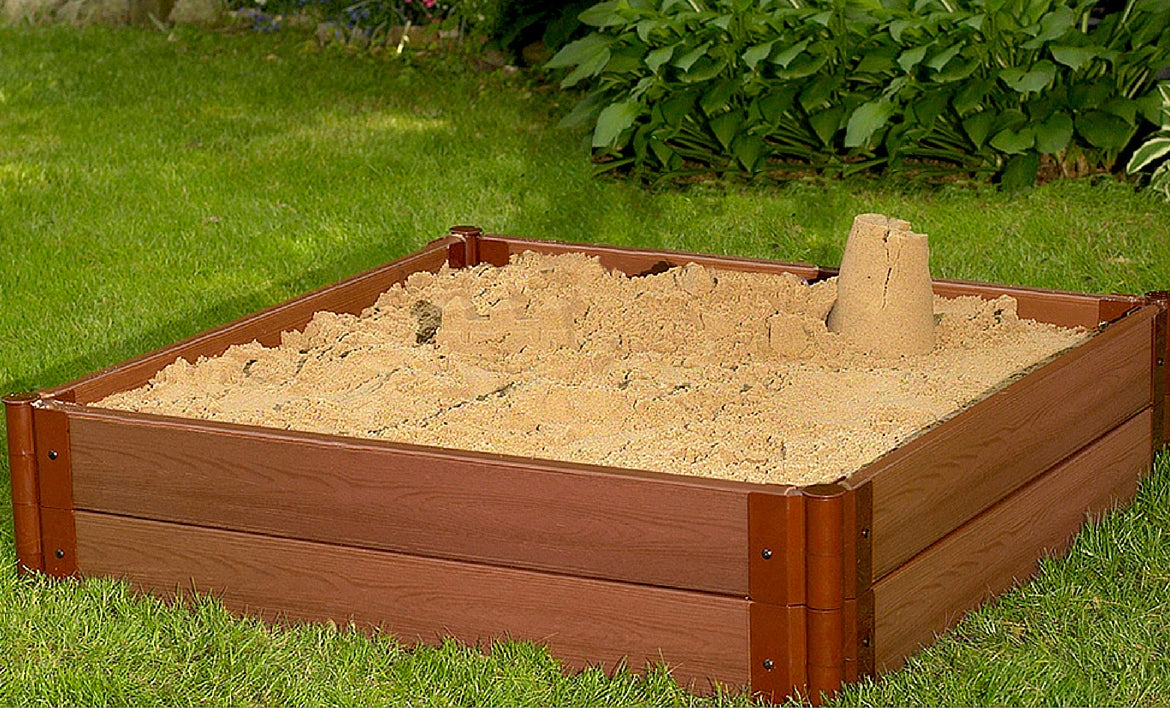 Tool-Free Classic Sienna Composite Square Sandbox Kit with deep sand and sandcastle, set on green grass in backyard