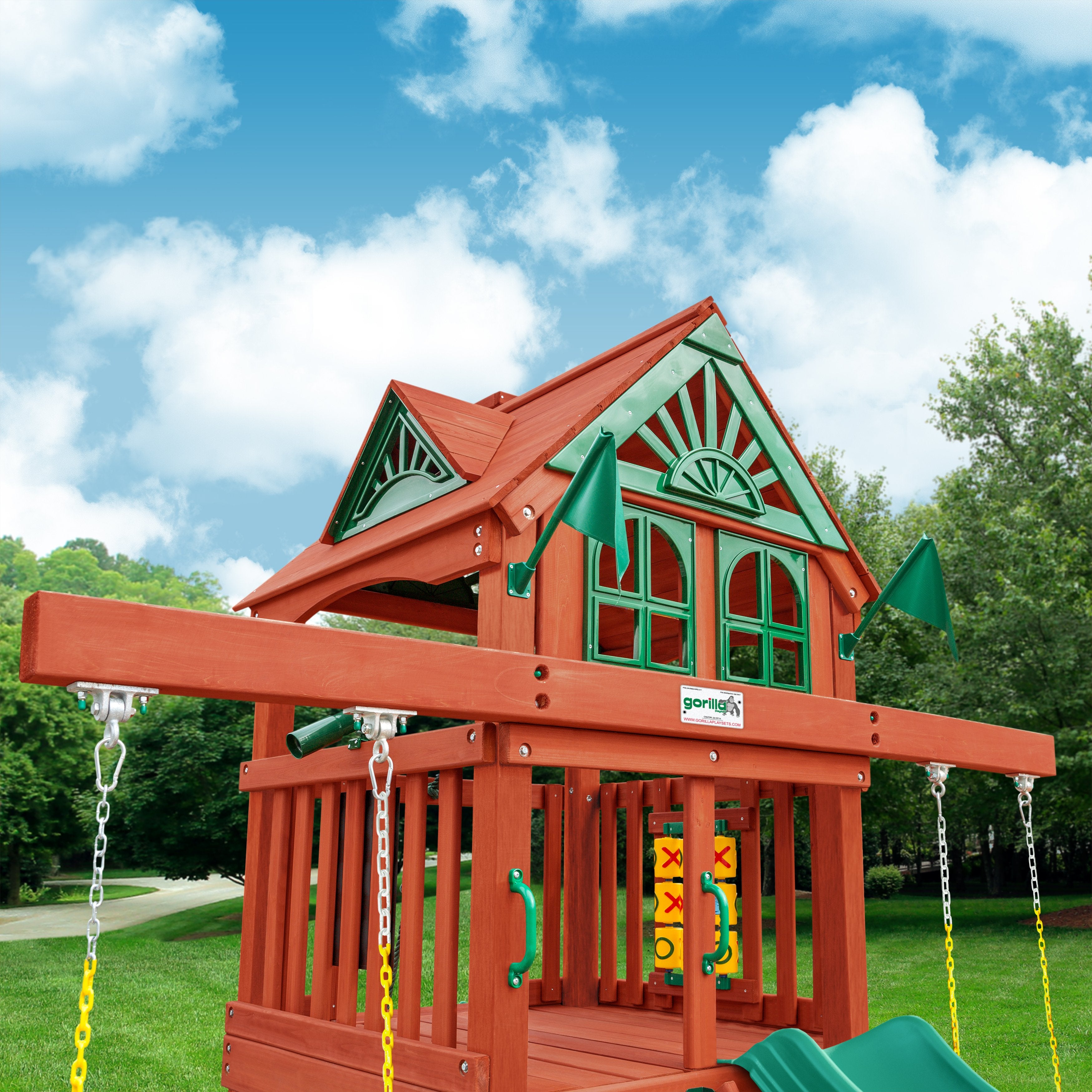 Wooden playset with redwood finish, green decorative roof, two belt swings, tic-tac-toe panel, and slide