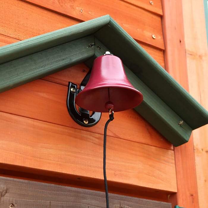 Red metal doorbell with black bracket and pull cord mounted on wooden playhouse exterior of a kids' swing set clubhouse