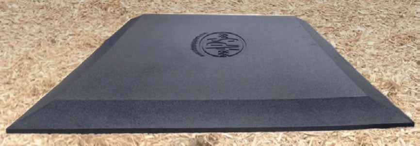 Heavy duty black rubber playground mat with beveled edges and textured waffle surface on mulch ground.