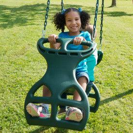 Child sitting on green dual glider swing with handles and footrests on grass outdoors